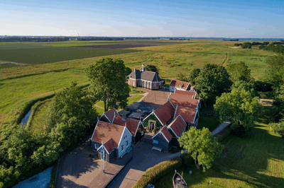Aerial view of a rural farmhouse complex surrounded by greenery and agricultural fields.